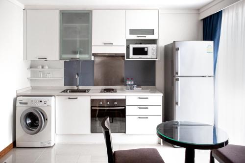 una cucina con elettrodomestici bianchi e tavolo in vetro di D Varee Montara Thonglor 25 a Bangkok