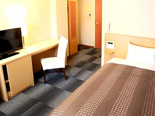 a hotel room with a bed and a desk and a television at HOTEL LiVEMAX BUDGET Chiba Mihama in Chiba