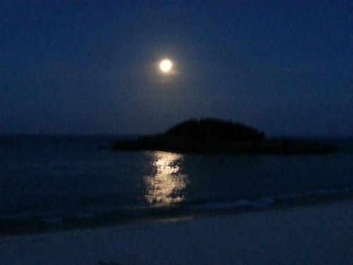a moon over an island in the ocean at night at Minshuku Myojoso in Yoron