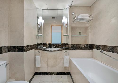 a bathroom with a tub and a toilet and a sink at Harbour Plaza Resort City in Hong Kong