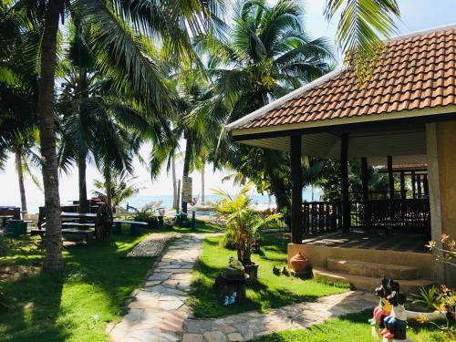 a yard with palm trees and a building at First Villa Beach Resort in Baan Tai