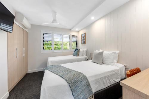 a bedroom with two beds and a flat screen tv at Pisces Apartment 5, Noosa Heads in Noosa Heads