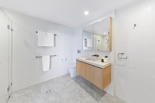a white bathroom with a sink and a toilet at Pisces Apartment 5, Noosa Heads in Noosa Heads
