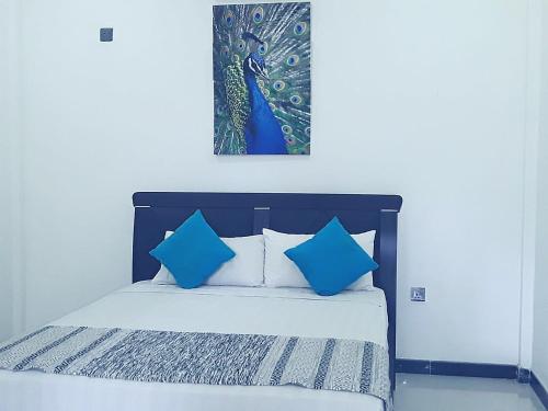 ein Bett mit blauen Kissen und einem Bild an der Wand in der Unterkunft My Home Guest in Polonnaruwa