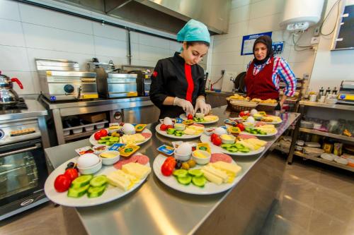 Zwei Frauen bereiten in einer Küche Essen zu, Teller mit Essen stehen bereit in der Unterkunft Business Palas Otel in Kocaeli