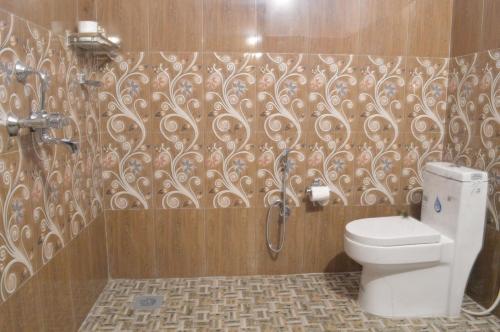 a bathroom with a toilet and a swirl pattern on the wall at Tharu Community Lodge in Kawasoti
