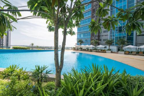 einen Pool mit Palmen und Gebäuden in der Unterkunft Diamond Twintower Apartment Hotel 鑽石雙星酒店式公寓 in Phnom Penh