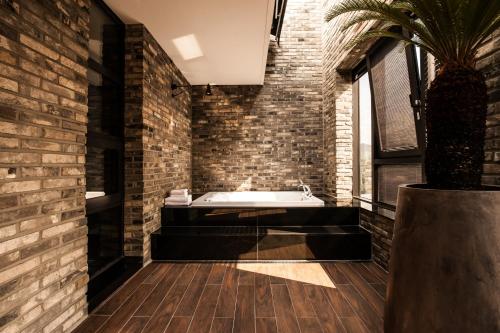 La salle de bains est pourvue d'une baignoire et d'un mur en briques. dans l'établissement SR Hotel Sadang, à Séoul