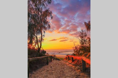 a pathway to the beach with a sunset in the background at Malibu Apartment - Peregian Beach in Peregian Beach