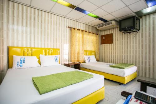 a room with two beds and a television in it at Bualuang HOTEL in Ang Thong