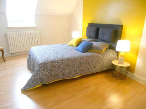 ein Schlafzimmer mit einem Bett mit einer blauen Decke und 2 Lampen in der Unterkunft Maison de 3 chambres avec jardin clos et wifi a Airvault in Airvault