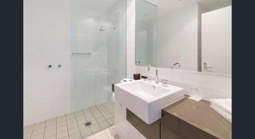 La salle de bains blanche est pourvue d'un lavabo et d'une douche. dans l'établissement Magenta Shores 3 Bedroom Villa, à Magenta