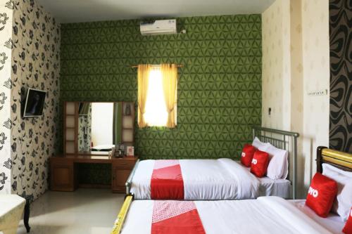 um quarto com 2 camas com paredes verdes e almofadas vermelhas em OYO 1722 Villa Ciparay Indah Syariah em Garut