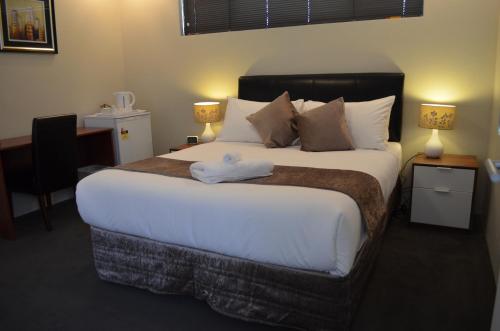 1 dormitorio con 1 cama grande con sábanas y almohadas blancas en Ellard Bed & Breakfast en Perth