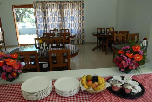 a table with plates and a bowl of fruit on it at Holiday Heaven Munnar in Chinnakanal