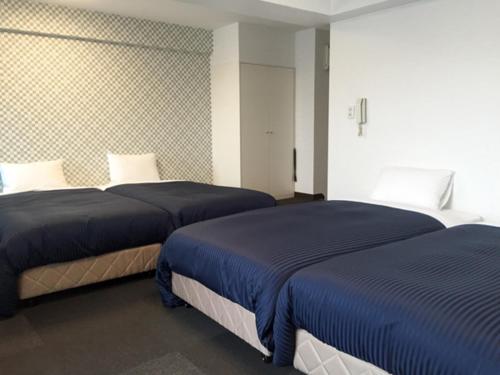 2 bedden in een hotelkamer met blauwe lakens bij HOTEL LiVEMAX BUDGET Fuchu in Fuchu