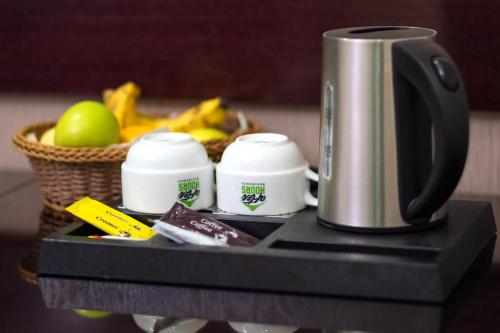 a coffee maker and a basket of fruit on a table at After Hours Residence in Dhaka