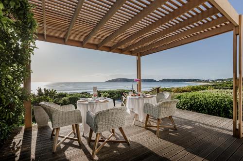 a dining room table with chairs and umbrellas at The Robberg Beach Lodge - Lion Roars Hotels & Lodges in Plettenberg Bay