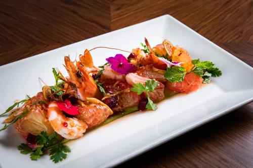 a white plate with shrimp and vegetables on a table at Oakwood Residence Hanoi in Hanoi