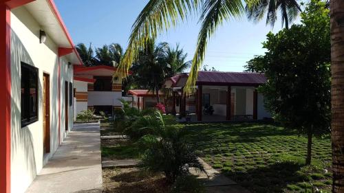 uma casa com uma palmeira em frente a um quintal em KJ Danish Inn em Garcia Hernandez