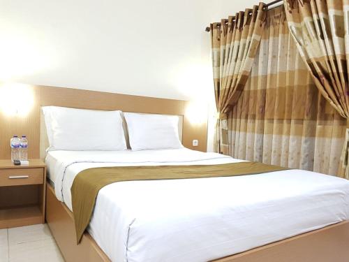 um quarto com uma cama grande e lençóis brancos em Morse Guest house em Malang