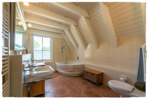 a large bathroom with a tub and a sink at Reetdachhaus mit Schwimmteich in Krienke in Rankwitz