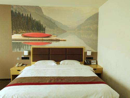 una camera da letto con un grande letto e un dipinto sul muro di Thank Inn Plus Hotel Jiangxi Fuzhou Jinxi County Government Square a Fuzhou