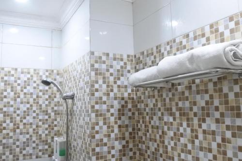 Łazienka z prysznicem wyłożona jest brązowymi i białymi kafelkami. w obiekcie Morse Guest house w mieście Malang