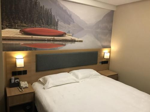 a bedroom with a bed with a painting on the wall at Thank Inn Plus Hotel Jiangsu Taizhou Gaogang Port Middle School in Taizhou