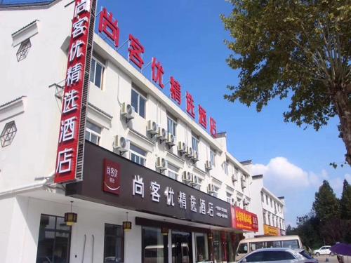 un gran edificio blanco con un cartel. en Thank Inn Plus Hotel Anhui Chizhou Jiuhuashan Scenic Area Yonghua Road, en Chizhou