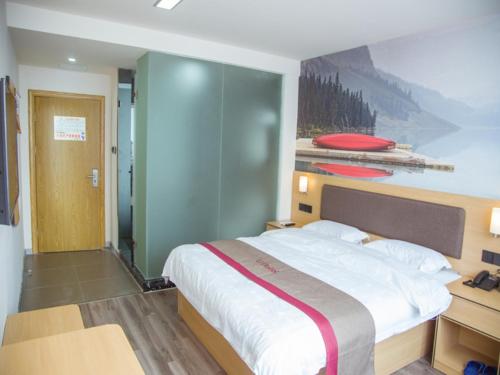 a bedroom with a large bed with a painting on the wall at Thank Inn Plus Hotel Jiangxi Nanchang Gaoxin Development Zone 2nd Huoju Road in Nanchang