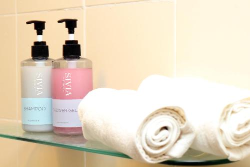 a shelf with three bottles of soap and towels at Sky Silk Decoration House in Patong Beach