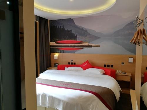 een slaapkamer met een groot bed en een schilderij aan de muur bij Thank Inn Plus Hotel Guangdong Zhaoqing Gaoyao City Yaonan 2nd Road in Zhaoqing