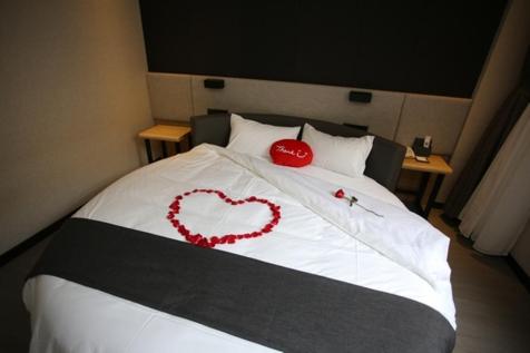a bed with two heart decorations on it at Thank Inn Plus Jiangsu Zhenjiang Jiangkou District Hongdou Square in Zhenjiang