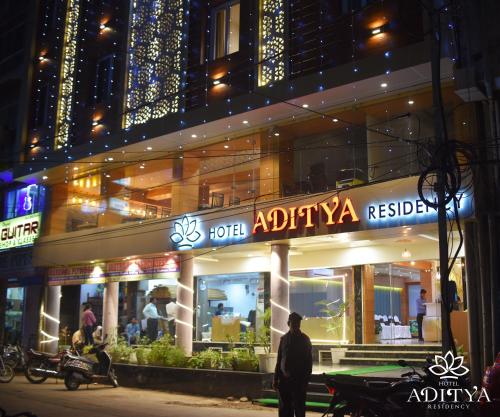ein Mann steht nachts vor einem Geschäft in der Unterkunft Hotel Aditya Residency in Bhopal