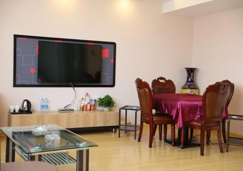 sala de estar con mesa y TV de pantalla plana en Thank Inn Plus Hotel Shandong Qingdao Jimo Development Zone New Government en Qingdao