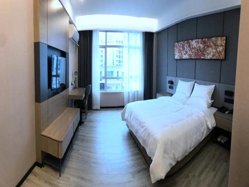 a hotel room with a bed and a television at Up And In Guangdong Zhongshan West District Caihong Street in Zhongshan