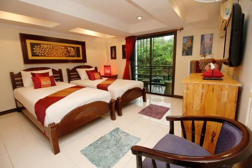 a bedroom with two beds and a tv and a chair at Sky Silk Decoration House in Patong Beach