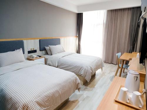 a hotel room with two beds and a table at Up And In Anhui Chizhou Guichi DistrictAnhui University of Engineering in Chizhou