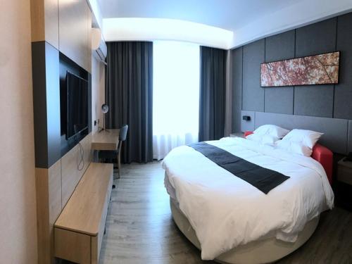 a hotel room with a bed and a television at Up And In Guangdong Zhongshan West District Caihong Street in Zhongshan
