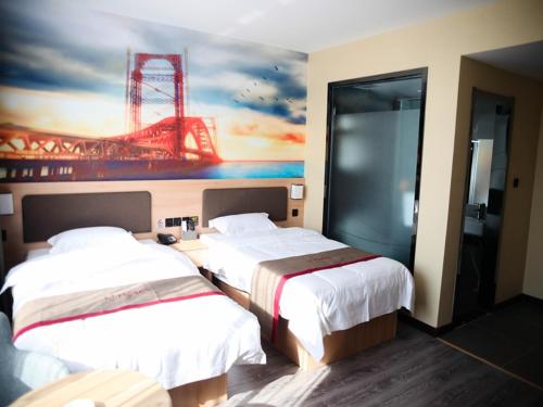 two beds in a hotel room with a painting on the wall at Thank Inn Plus Hotel Hebei Cangzhou Botou Development Zone Sanjing Road in Cangzhou