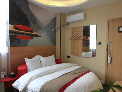 ein Schlafzimmer mit einem großen Bett und einem Gemälde an der Wand in der Unterkunft Thank Inn Plus Hotel Henan Zhengzhou Jinshui District Wenhua Road Chenzhai in Zhengzhou