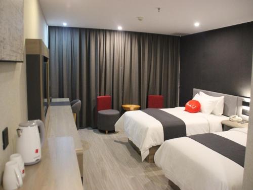 済寧市にあるThank Inn Plus Hotel Shandong Qufu Kongfuのベッド2台とデスクが備わるホテルルームです。