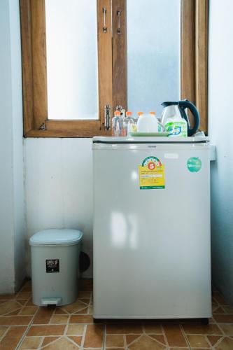 a small white refrigerator in a room with a trash can at Sabuy Chiangmai in Chiang Mai