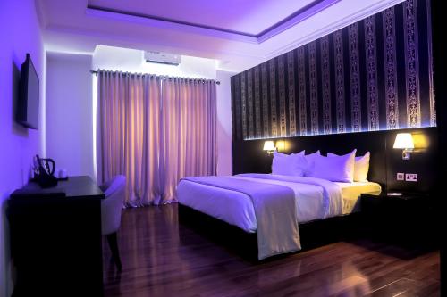 a bedroom with a king sized bed with purple lighting at BON Hotel Ikeja Residence in Ikeja