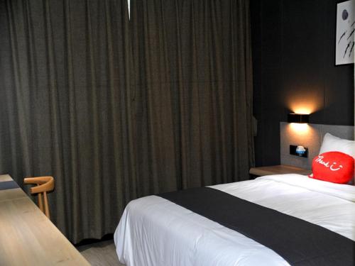 Habitación de hotel con cama con almohada roja en Up And In Fujian Fuzhou Minhou County Shangjie Town Fuzhou University City, en Fuzhou