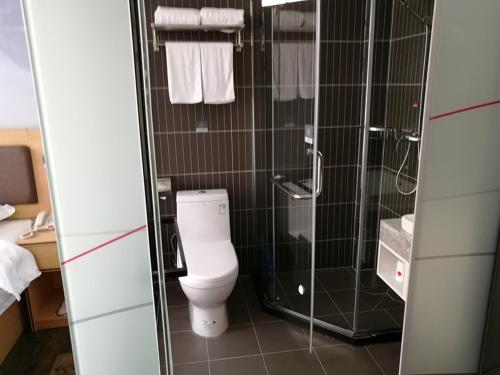 a bathroom with a toilet and a glass shower at Thank Inn Plus Hotel Guangdong Zhaoqing Gaoyao City Yaonan 2nd Road in Zhaoqing