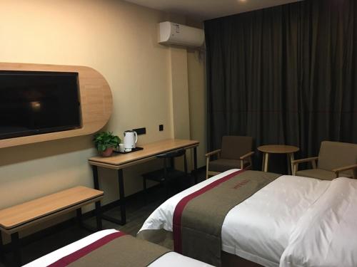 a hotel room with two beds and a desk and a tv at Thank Inn Plus Hotel Henan Sanmenxia Lingbao Changan Road in Sanmenxia