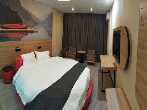 池州市にあるThank Inn Plus Hotel Anhui Chizhou Jiuhuashan Scenic Area Yonghua Roadのベッドとテレビが備わるホテルルームです。