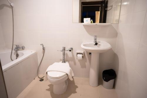 La salle de bains blanche est pourvue de toilettes et d'un lavabo. dans l'établissement Betong Hello Hotel, à Betong